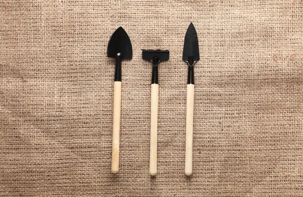 Çuval bezi üzerinde minyatür bahçe aletleri (tırmıklar, kürekler) seti