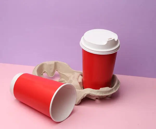 Two disposable cups for hot drinks with a tray on a pastel color background