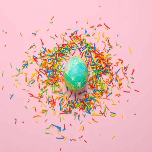 Renkli paskalya şekeri ve pembe arka planda yumurta. Yaratıcı yerleşim