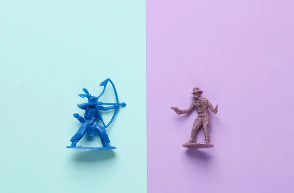Native American Indian and cowboy figurines on a pastel background. Wild West