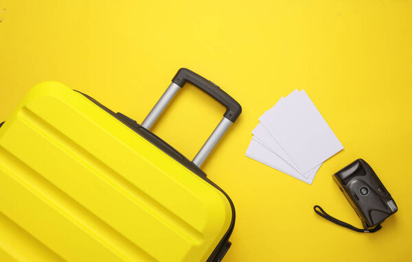 Желтый чемодан, дорожная сумка или сумка с ретро-камерой и макетами фотографий на желтом фоне. Летние каникулы, путешествия, концепция поездки. Вид сверху