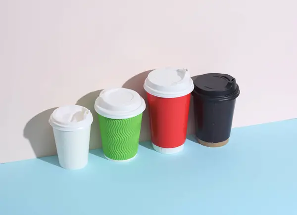 Set of various disposable cups for hot drinks on a pastel wall background