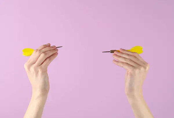 Hand holds darts on a purple background. Goal, business concept