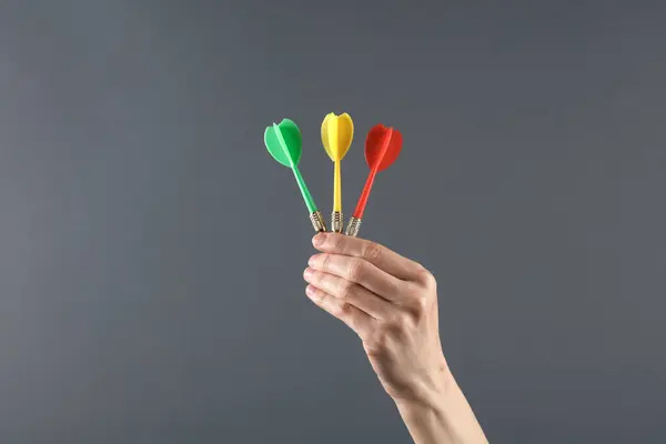 Hand holds darts on dark background. Goal, business concept