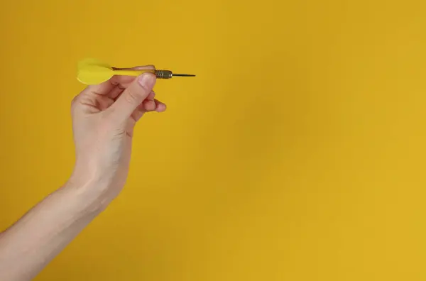 Hand holds darts on yellow background. Goal, business concept