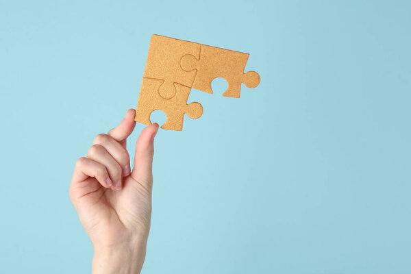 Hand holds golden puzzle pieces on blue background. Business concept, teamwork