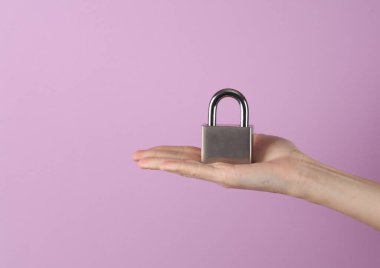 Mor pastel arka planda metal asma kilit tutan kadın.