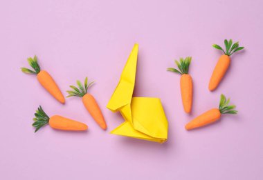 Mor pastel arka planda havuç olan Origami tavşanı. Paskalya konsepti