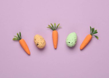 Mor arka planda renkli yumurtalı havuç. Kavramsal Paskalya natürmortu