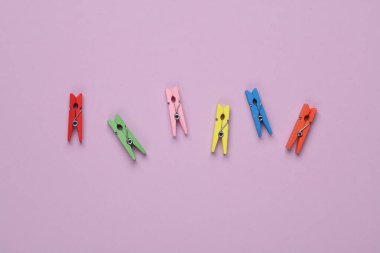 Mor arka planda bir sürü renkli mandal var.