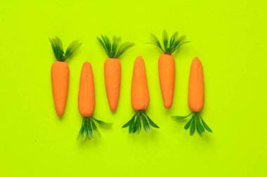 Yeşil arka planda plastik havuç. Asgari, kavramsal gıda natürmort, yaratıcı düzen