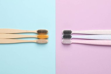 Pastel arka planda plastik ve eko bambu diş fırçaları. Üst görünüm