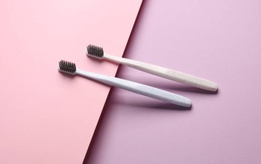 Pastel arka planda iki plastik diş fırçası. Ağız temizliği. Yaratıcı yerleşim