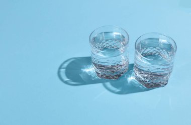 Yansımalı su bardakları ve mavi arka planda gölgeler. Minimalizm.