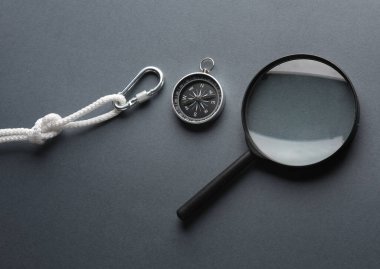 İp ve pusula ile karabina, koyu arka planda büyüteç. Turizm, dağcılık, açık hava aktiviteleri