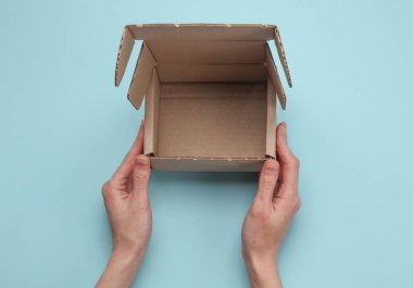 Mavi arka planda karton posta kutusu tutan eller