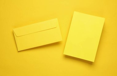 Sarı kapaklı not defteri ve sarı arka planda yüzen zarf.