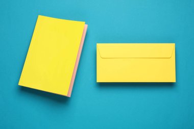 Sarı kapaklı not defteri ve mavi arkaplanda yüzen zarf.