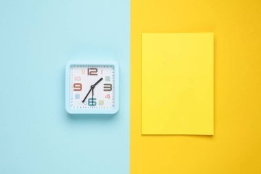 Renkli pastel arka planda saati olan not defteri. Üst görünüm