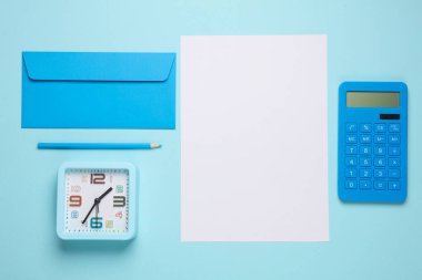 Zarflı beyaz kağıt, saat, mavi arka planda hesap makinesi. İş konsepti. Üst Manzara. Düz yatıyordu