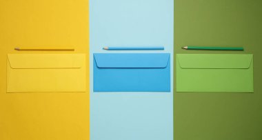 Renkli arka planda kalemleri olan üç renkli zarf. Üst Manzara. Kavramsal iş fotoğrafı