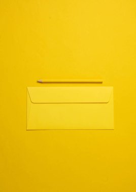 Sarı arka planda kurşun kalem olan sarı bir zarf. Minimalizm