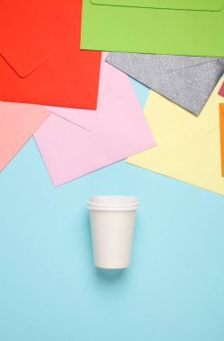 Bir sürü renkli zarf ve mavi arka planda kahve.