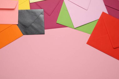 Pembe arkaplanda fotokopi alanı olan birçok renkli zarf