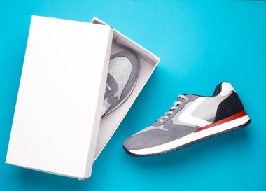 Mavi arka planda kutusu olan yeni gri koşu ayakkabıları. Sıradan spor ayakkabılar..