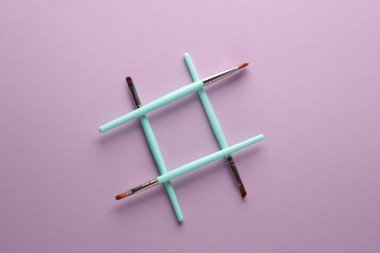 Mor renkli arka planda hashtag şeklinde makyaj fırçası