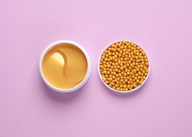 Altın göz bantlı kavanoz ve mor arka planda makyaj tozu topları. Güzellik konsepti. Üst görünüm