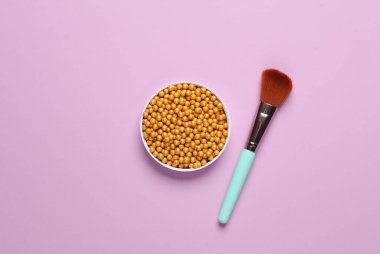 Makyaj altın pudra topları ve mor arka planda fırça. Güzellik konsepti. Üst görünüm