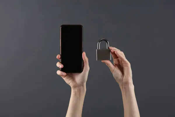 Protection of personal information. Hands holding smartphone with padlock on dark gray background