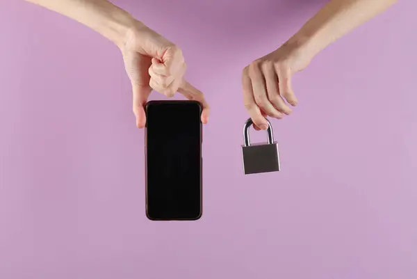 Protection of personal information. Hands holding smartphone with padlock on purple background