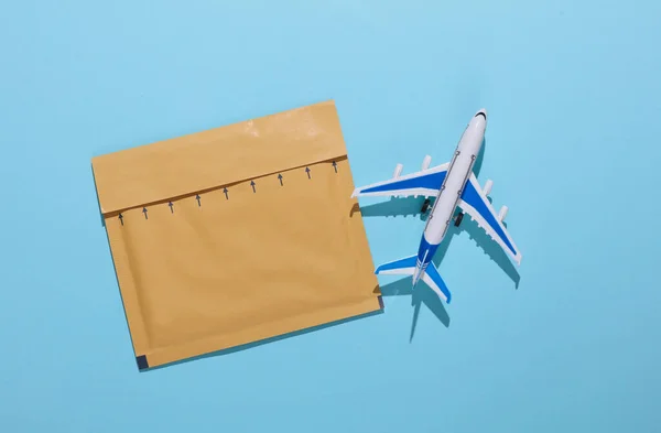 Parcel envelope and toy air plane on blue background. Delivery, cargo transportation