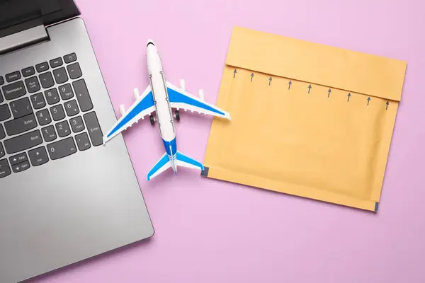 Laptop, Parcel envelope and toy air plane on blue background. Delivery, cargo transportation, online shopping