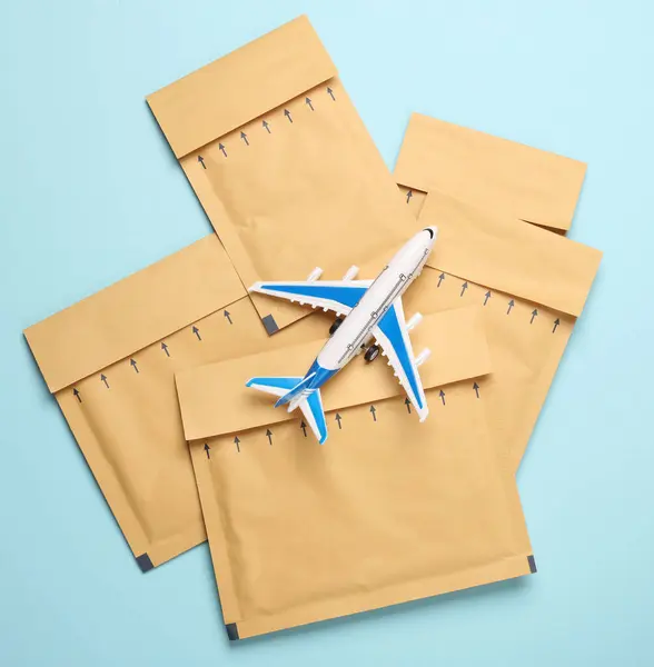 Parcel envelopes and toy air plane on blue background. Delivery, cargo transportation. Top view