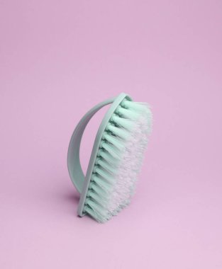 Pembe arka planda temizlik için mavi plastik fırça