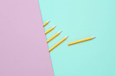 Pastel arka planda sarı doğum günü mumları. Minimalizm partisi konsepti