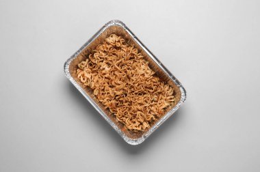 Gri arka planda folyo kasesinde hazır şehriye. Üst görünüm