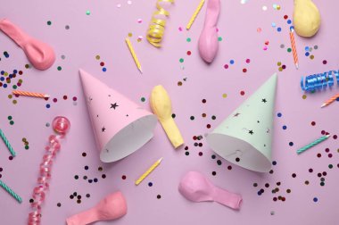 Pastel arka planda doğum günü konisi kapakları, konfeti, mum ve balonlar. Parti konsepti. Üst görünüm