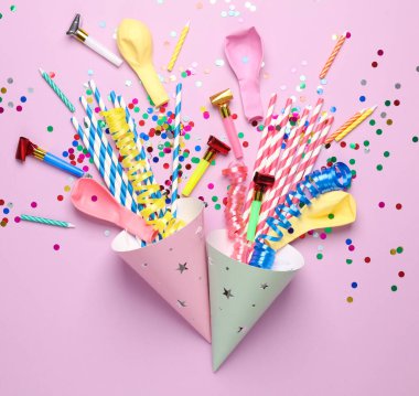 Pembe arka planda parti aksesuarları olan doğum günü konisi şapkaları. Üst görünüm