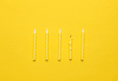 Sarı arka planda sarı doğum günü mumları. Minimalizm partisi konsepti