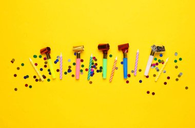 Sarı arka planda konfetili doğum günü boynuzları. Parti konsepti