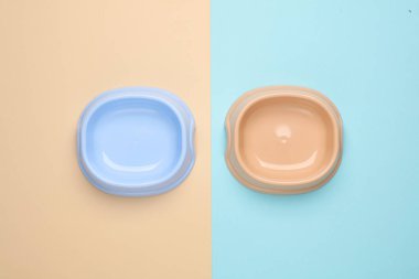 Pastel arka planda iki boş evcil hayvan kasesi.