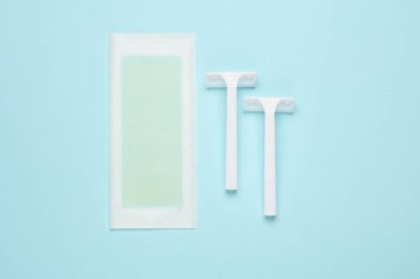 Tüy dökümü için balmumu şeridi ve mavi arka planda tıraş bıçağı. Üst görünüm