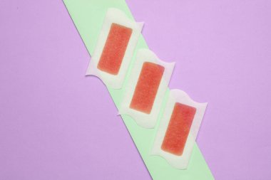 Pastel arka planda tüy dökülmesi için balmumu şeritleri. Güzellik konsepti. Üst görünüm