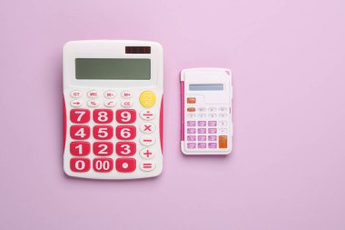 Pembe arka planda büyük ve küçük hesap makineleri. Üst görünüm
