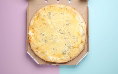 Mavi-pembe arka planda kutuda peynirli pizza. Üst görünüm