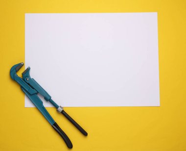 Sarı zemin üzerinde boş kağıt levha ile metal ayarlanabilir anahtar.